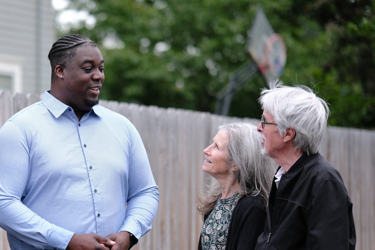 Luc talking with a couple of neighbors by a fence